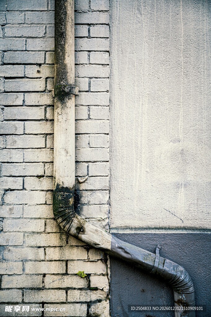 老旧砖墙旁的金属管道