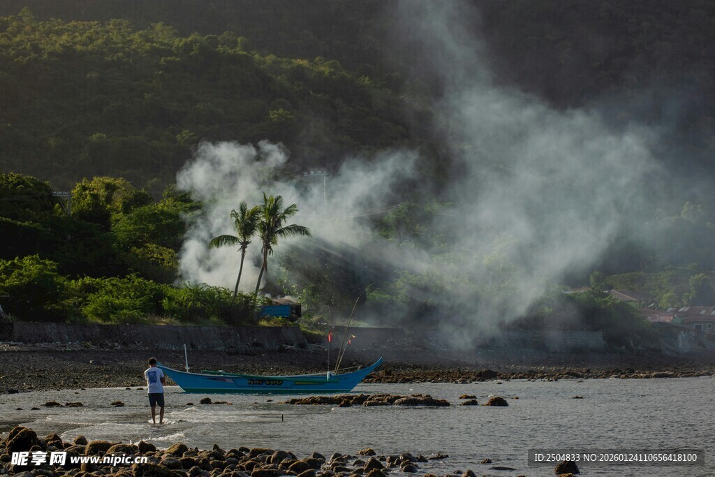 海边小船旁升腾的烟雾