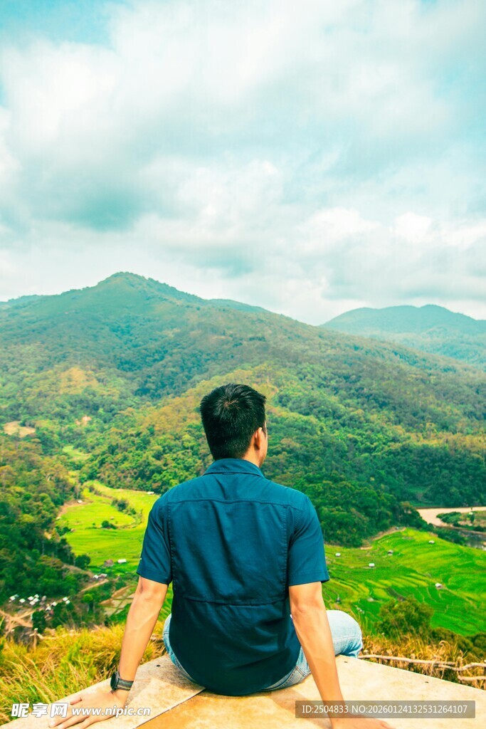 男子坐于山巅赏秀丽风光