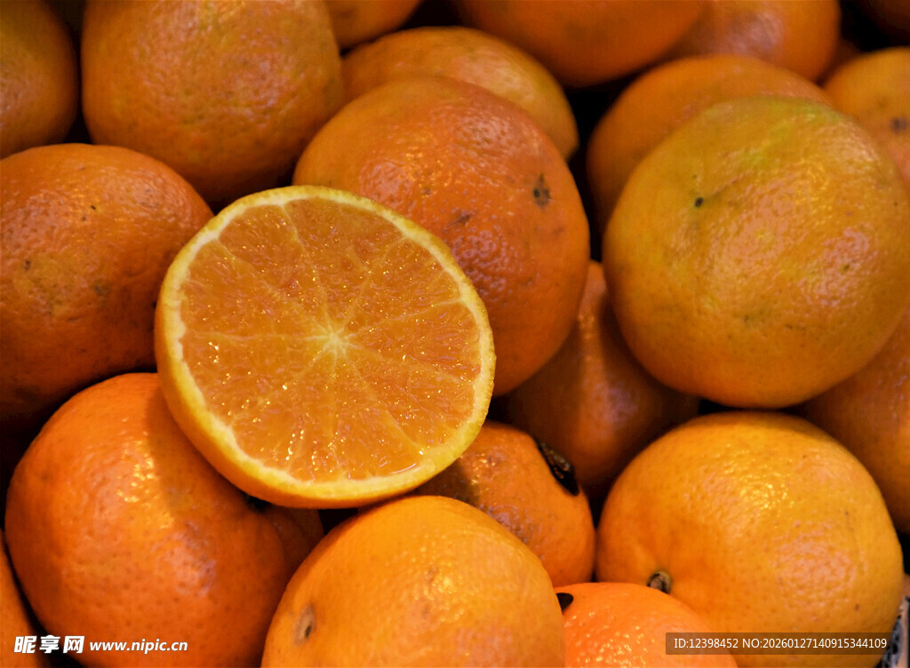 一堆鲜橙中的半颗切开橙