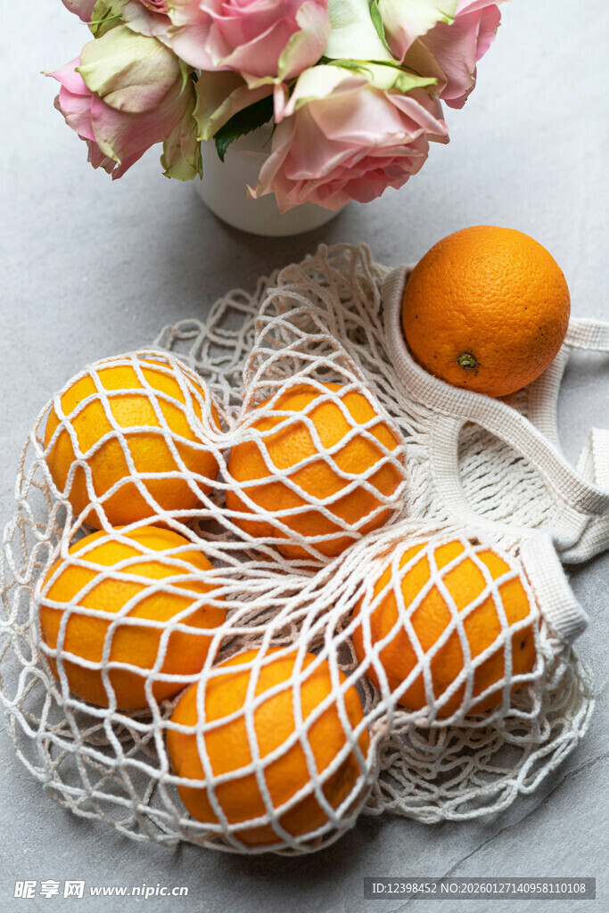 网兜中的新鲜橙子与花束