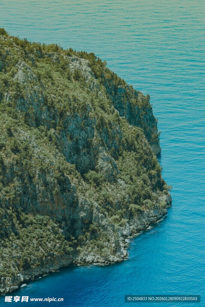 蓝色海岸边的葱郁山崖