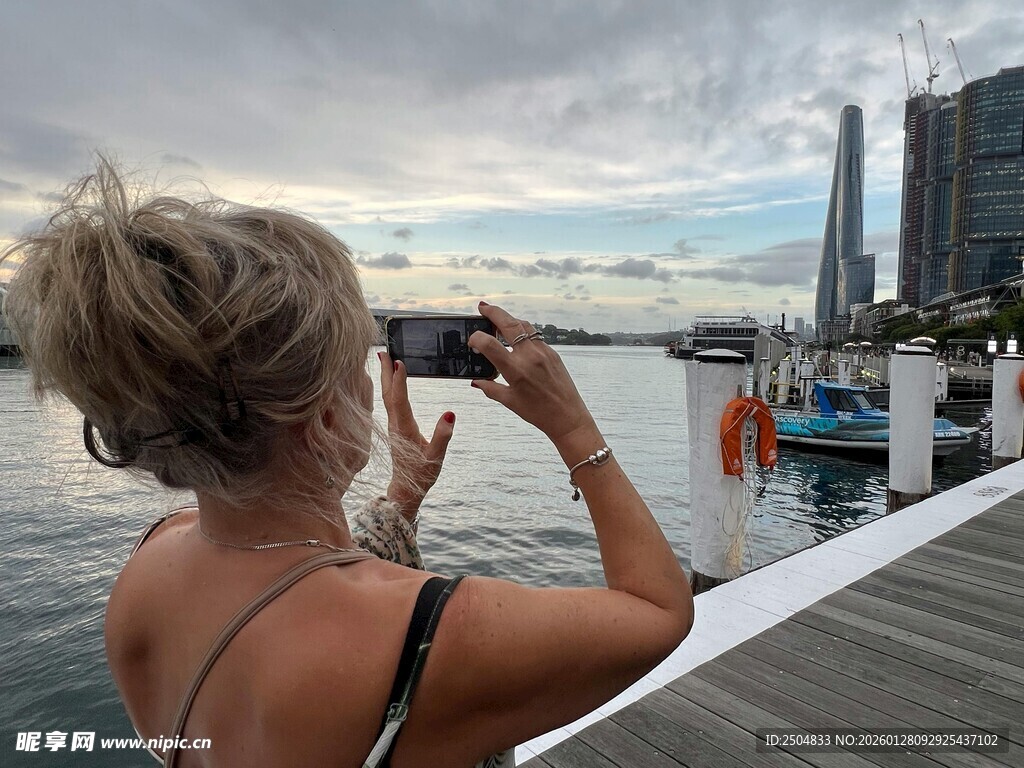 女子码头边拍摄城市风景