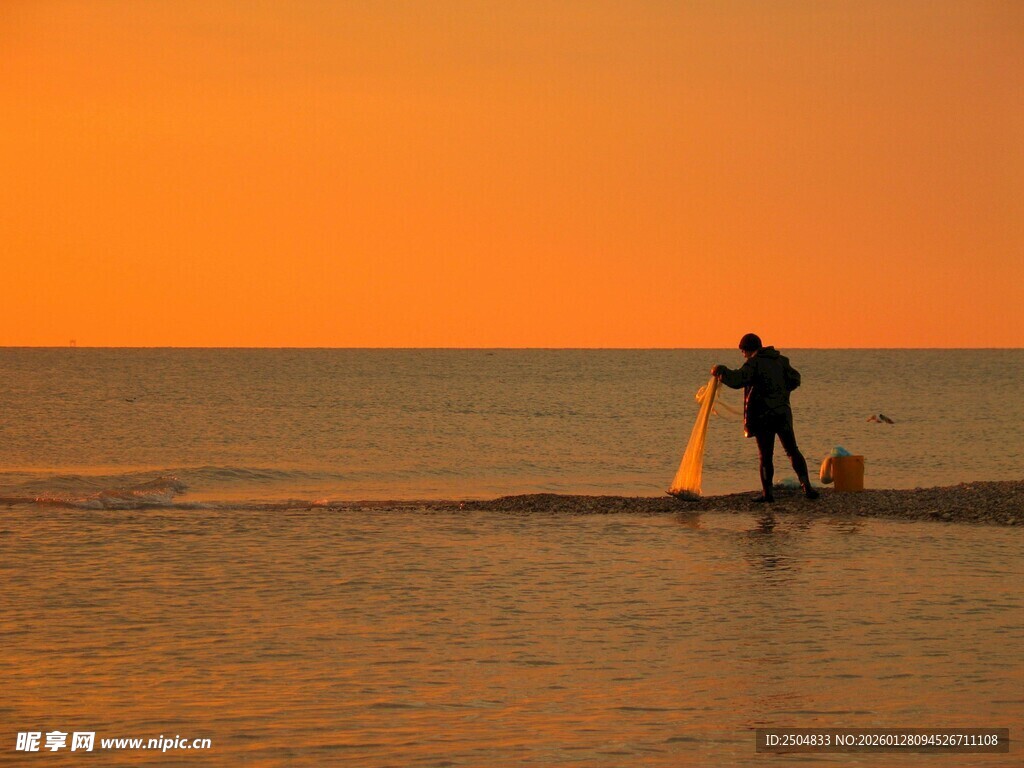 夕阳下海边的垂钓者