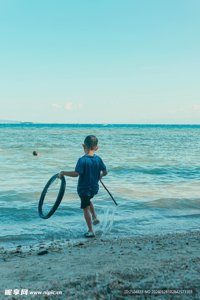 海边孩童持圈持杆玩耍