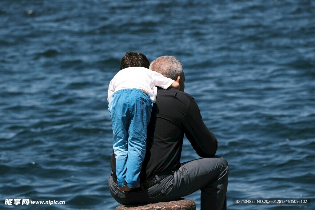 父子海边相依眺望远方