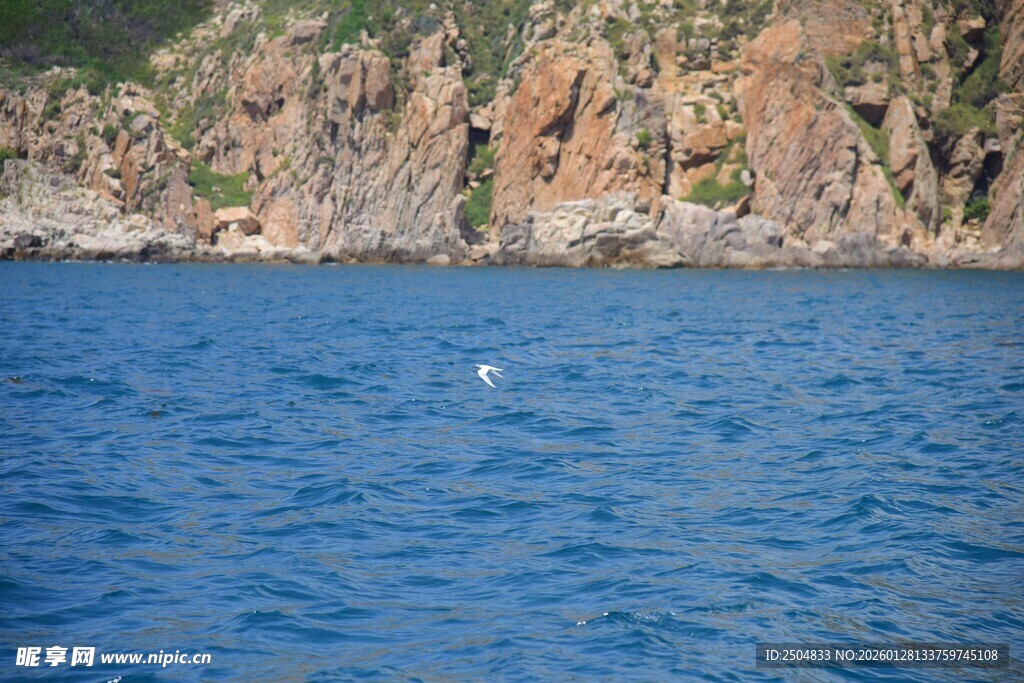 蓝色水域旁的岩石海岸
