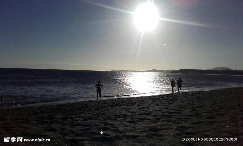 夕阳下的海滩漫步身影