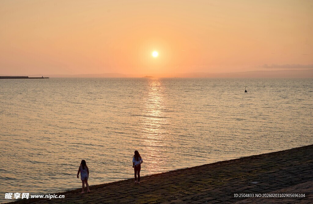 夕阳下海边漫步的两人