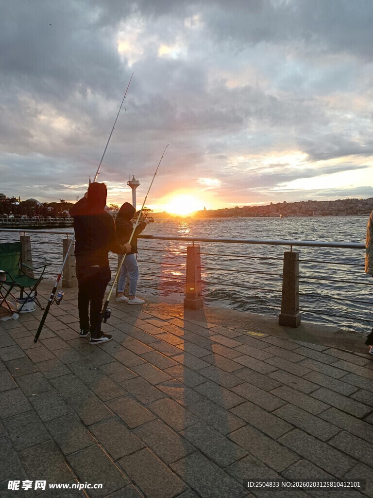 夕阳下的海边垂钓者