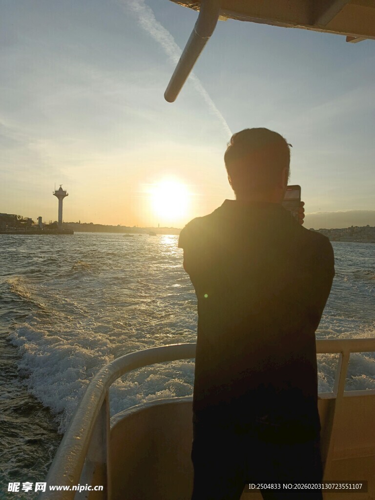 海上夕阳下的乘船拍照者