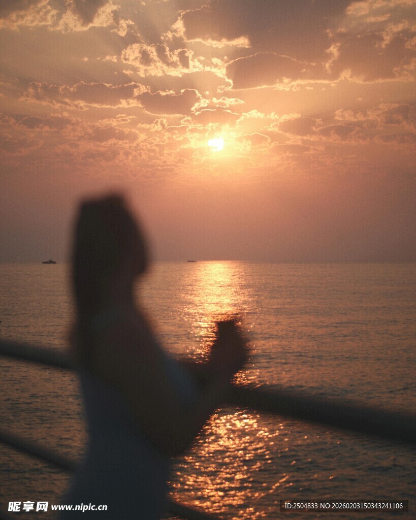 夕阳下女子海边惬意举杯