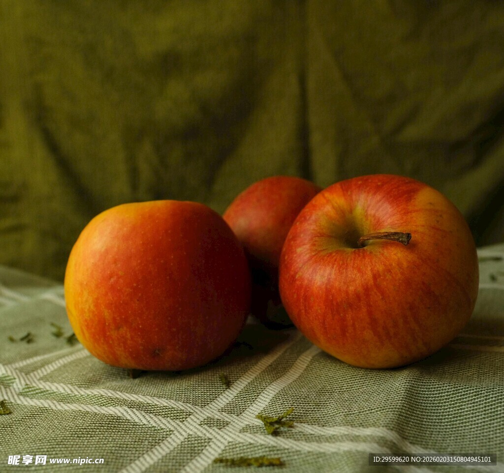 三个红苹果置于桌布上