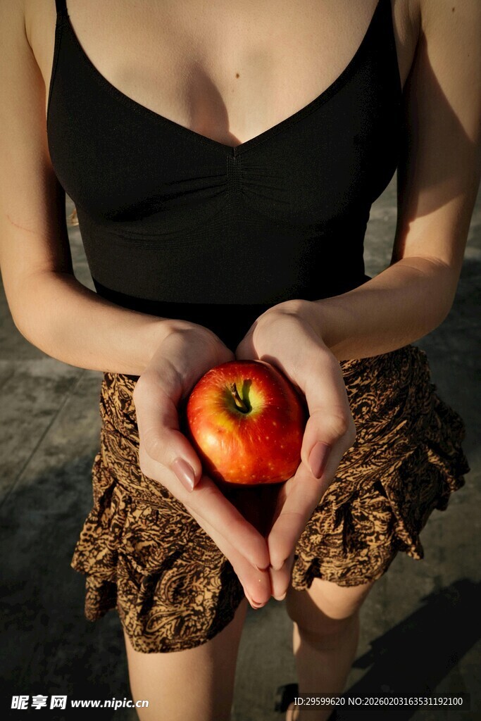 女子双手捧红心形苹果