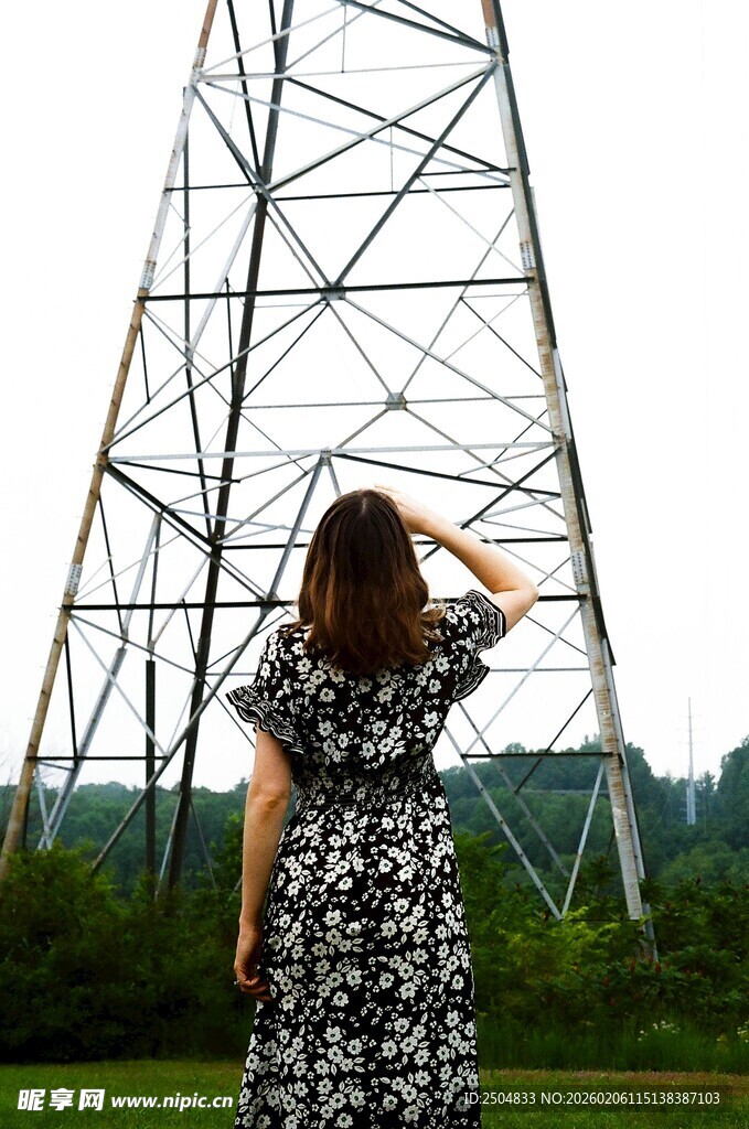 女子仰观高耸输电铁塔