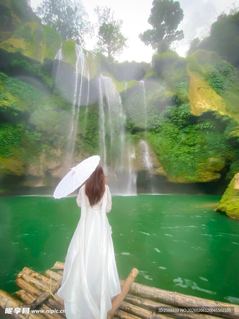 白衣女子于瀑布竹筏撑伞赏景