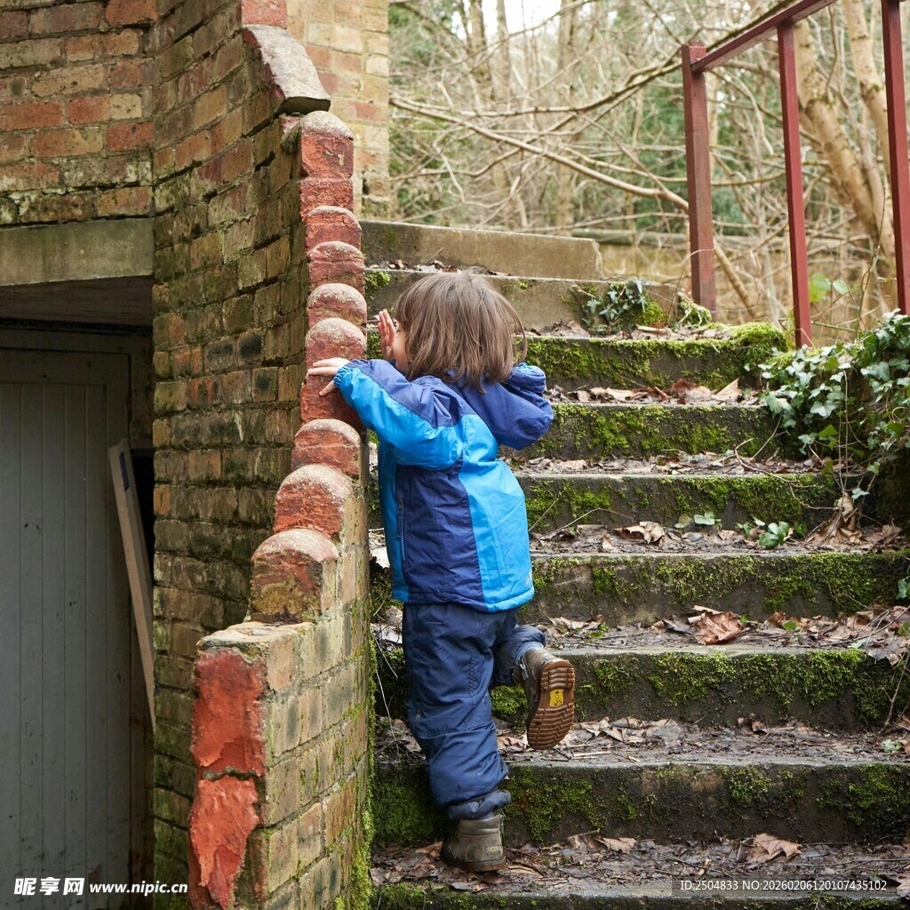 小孩在户外砖墙旁探索