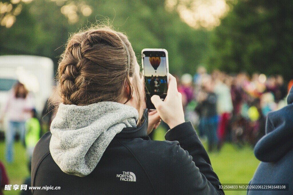 女子户外用手机拍摄人群