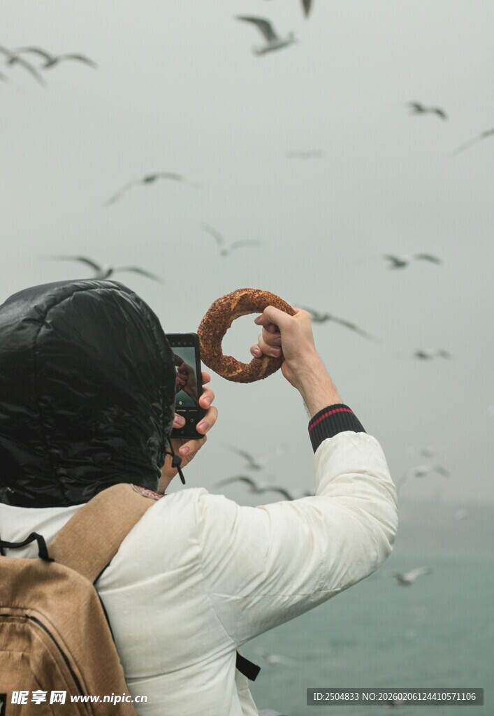 女子海边举圈逗飞海鸥