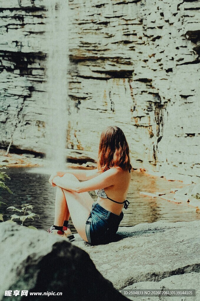 女子坐于瀑布前享受宁静