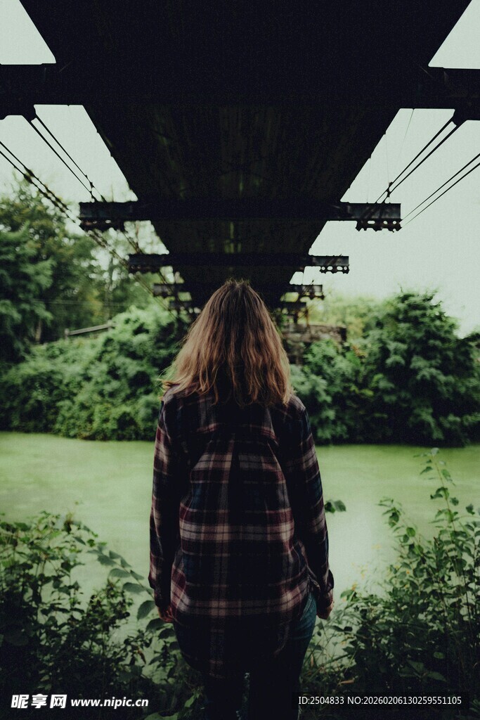女孩背对镜头立于桥底