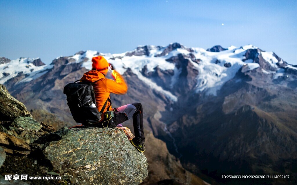 登山者坐于雪山之巅赏景