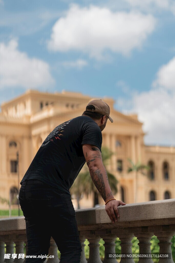 男子凭栏眺望宏伟建筑