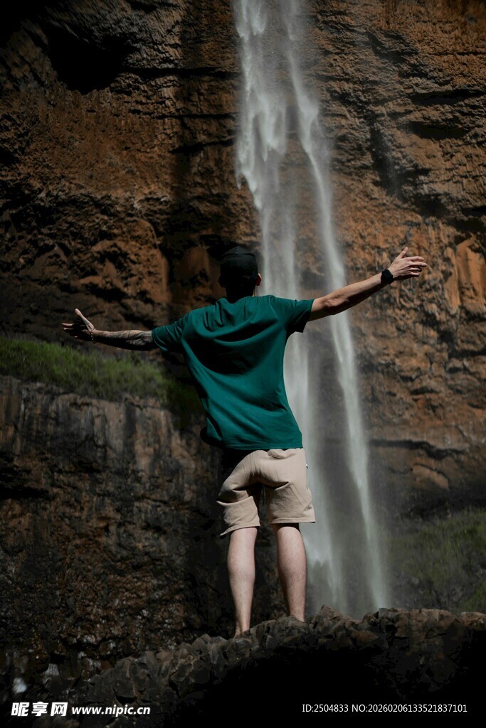 男子于瀑布前舒展双臂