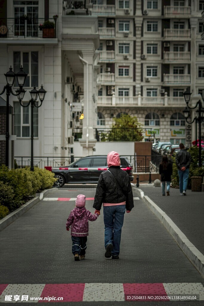 母亲带孩子走在小区道路上