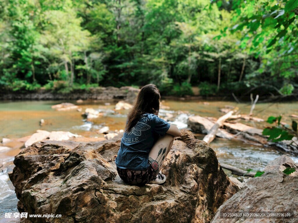 女子独坐溪边岩石赏景