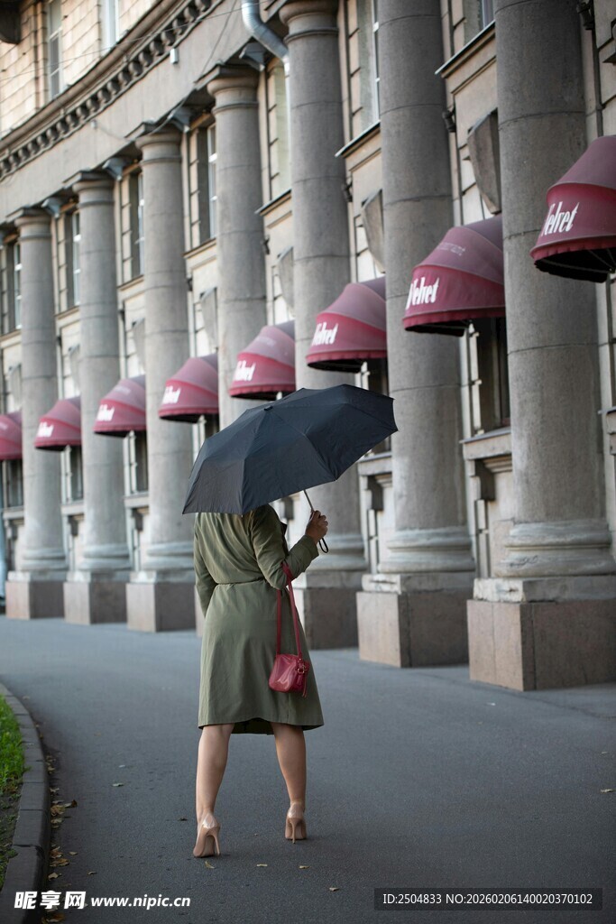 雨中撑伞走过古典建筑旁