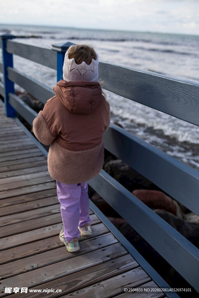 小女孩在海边木栈道眺望