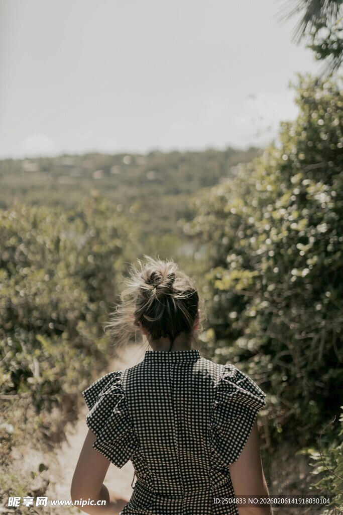 女子漫步于绿意盎然的小径