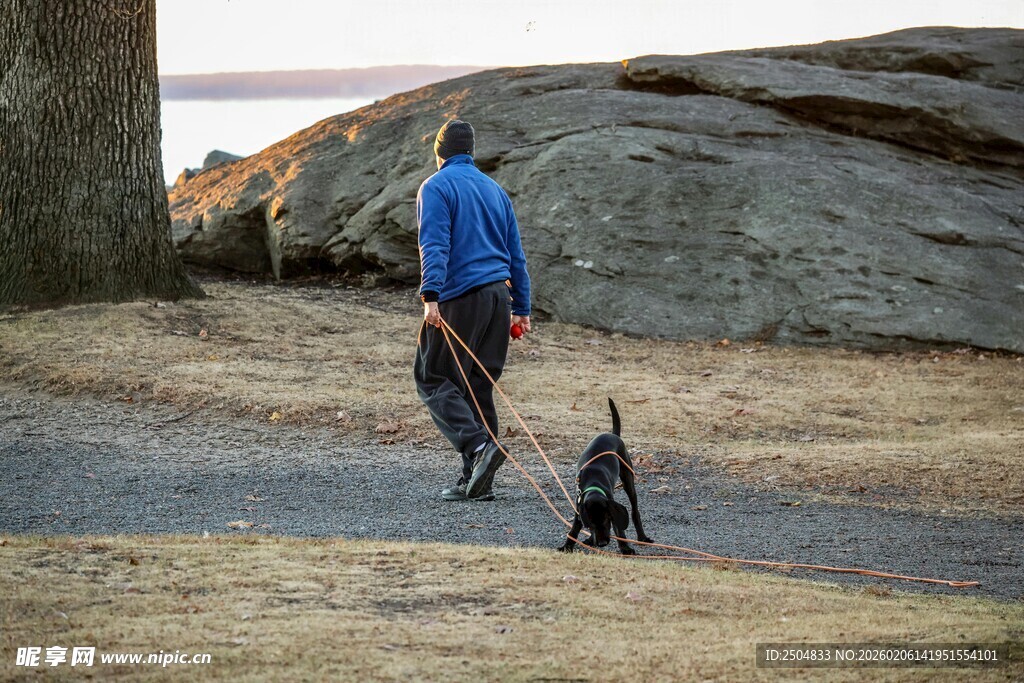 男子携狗漫步户外小道