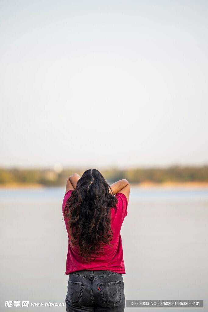 红衣女子湖畔举臂赏景