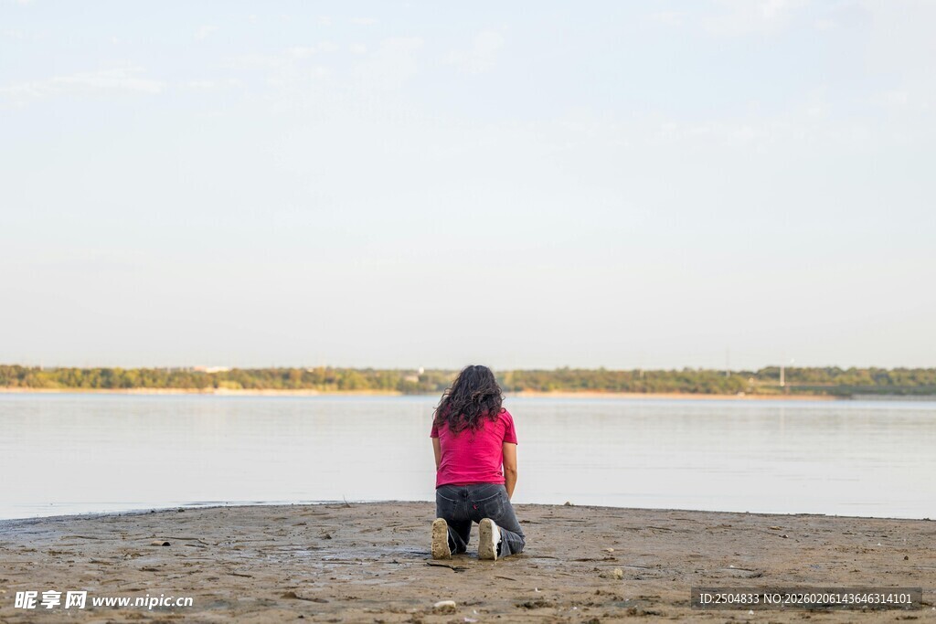 女孩独坐在湖边沙滩