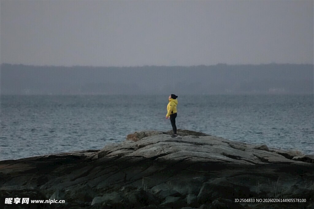 孤身立岩望海的男子