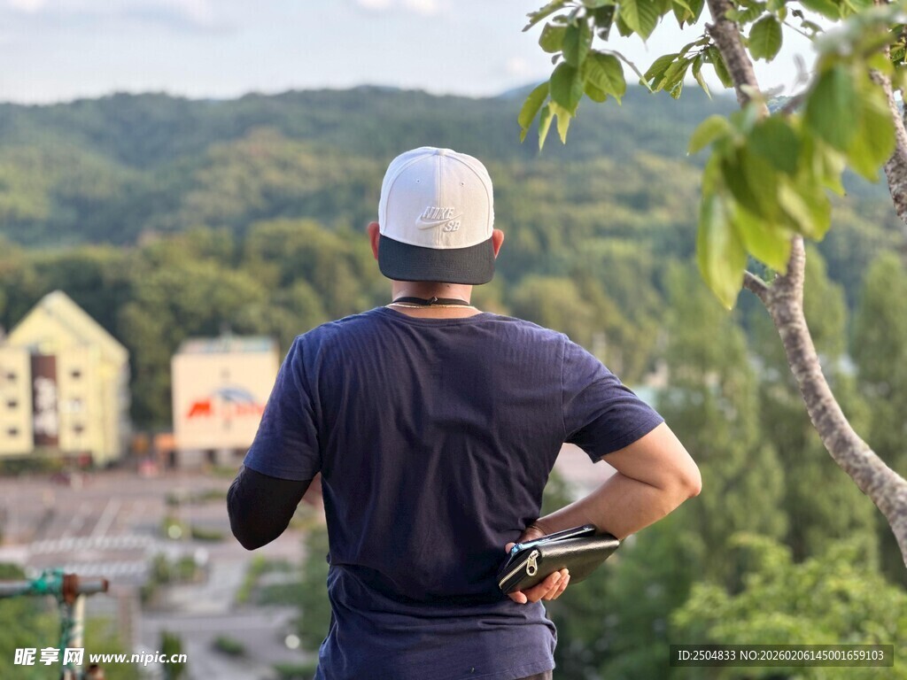 男子背手眺望山间景色