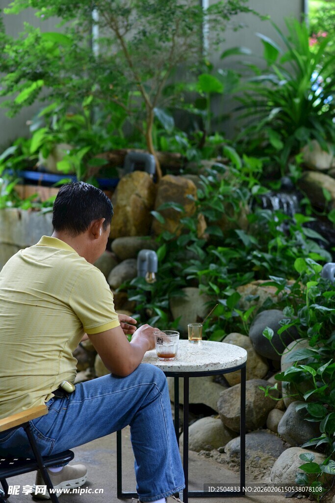 男子于绿植间专注下棋