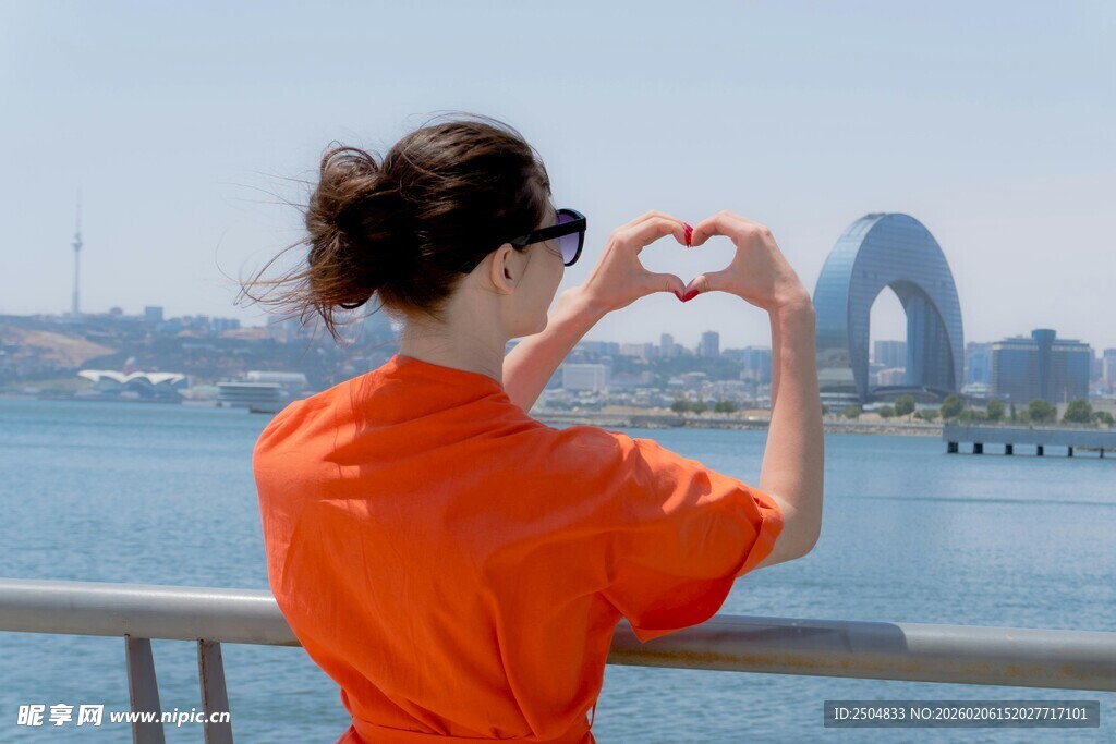 红衣女子海边比心赏景