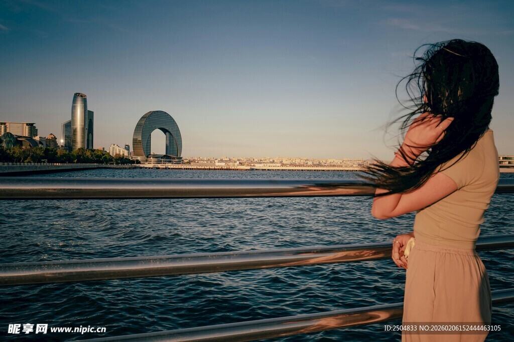 海边女子凭栏眺望城市景