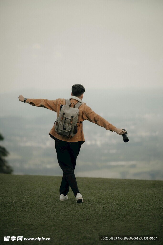 山顶上张开双臂的背包客