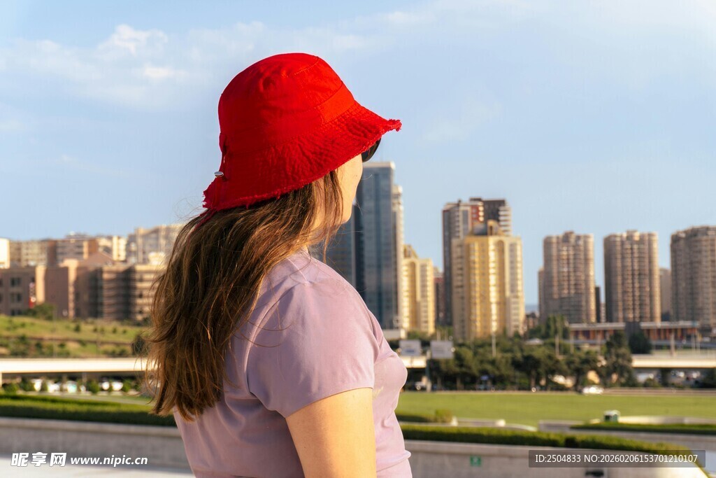 戴红帽女子眺望城市风景