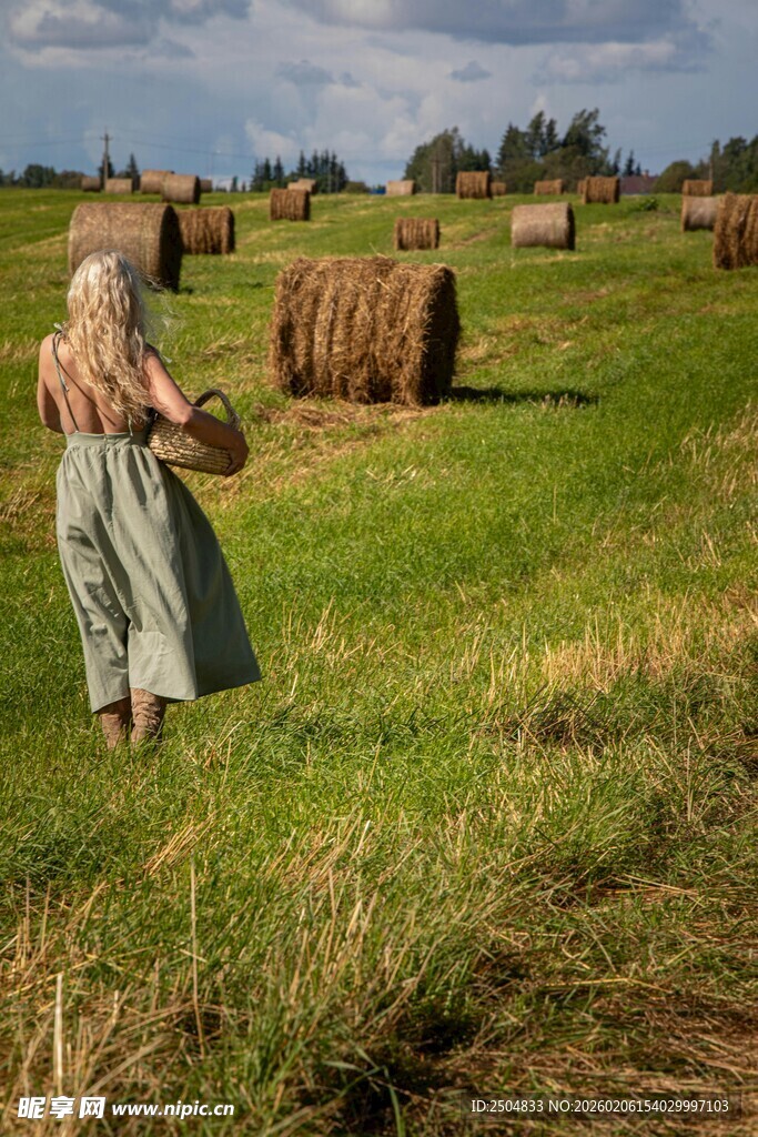 田园女子提篮漫步于草垛间