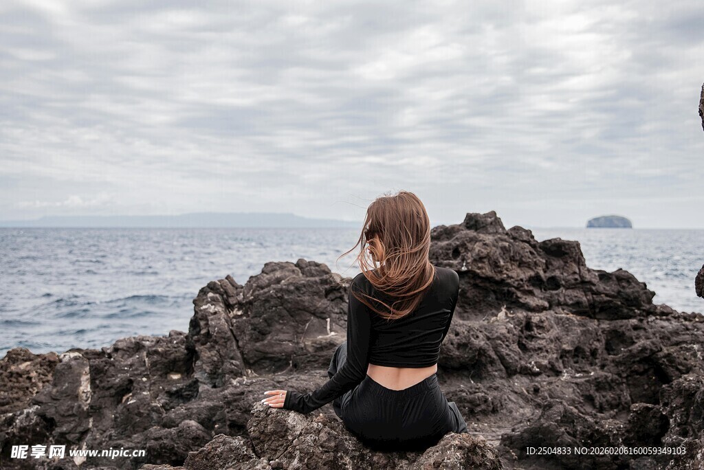 女子坐于礁石眺望大海