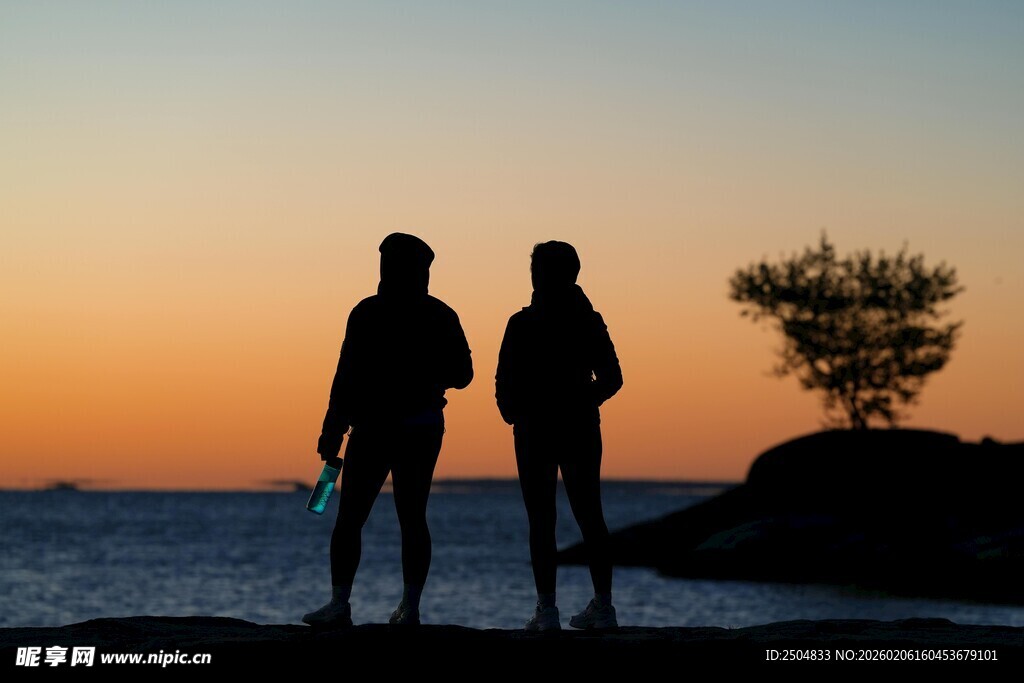 夕阳下海边的两人剪影