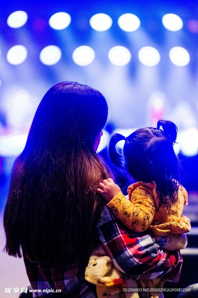 母亲怀抱孩子观舞台灯光