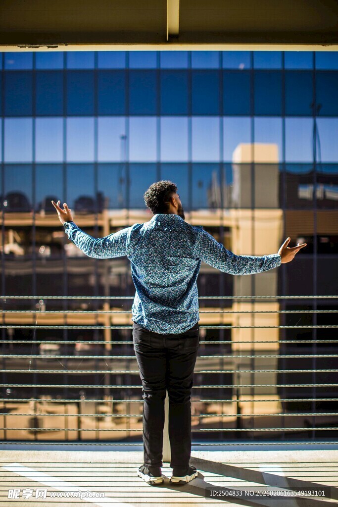 男子于高楼前舒展双臂