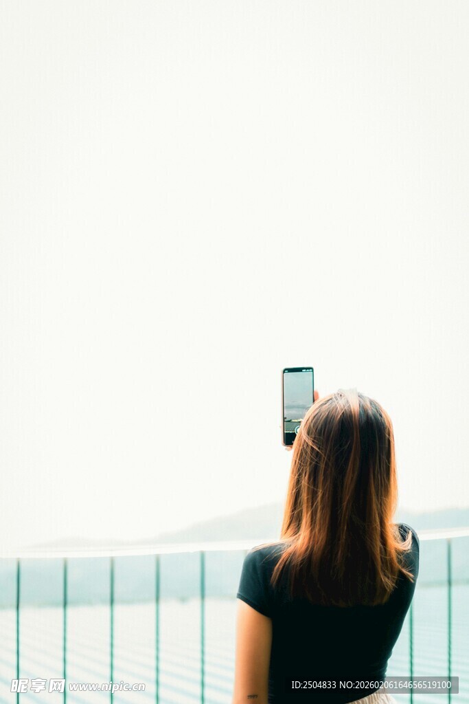 女子持手机拍照背影