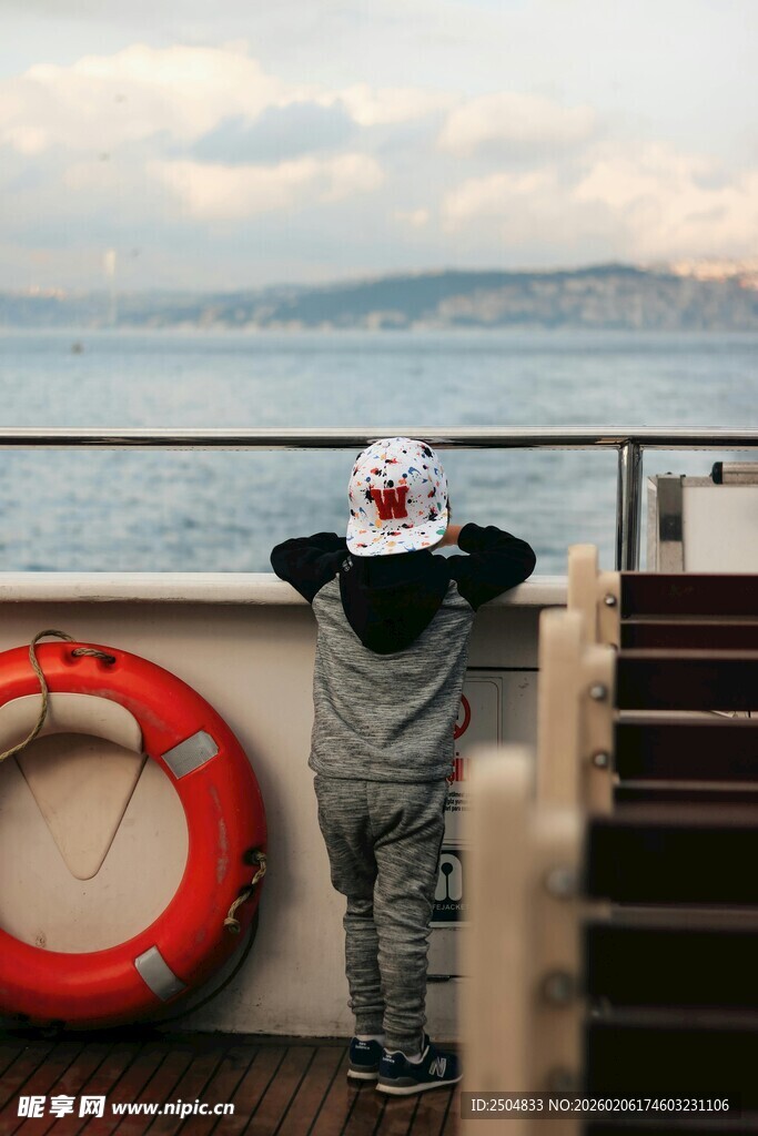 小孩船边眺望远方海景